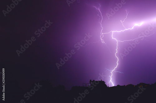 flash of lightning in the night sky color it in an incredibly beautiful violet color illuminating the trees