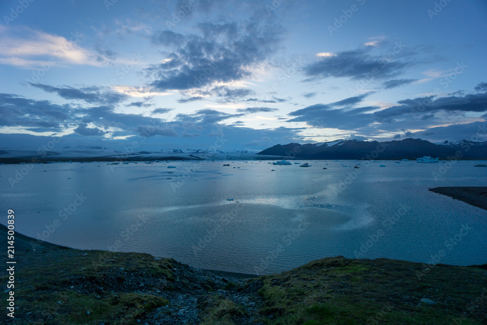 Iceland - Coast of glacier lagoon joekulsarlon with floating ice floes at midnight