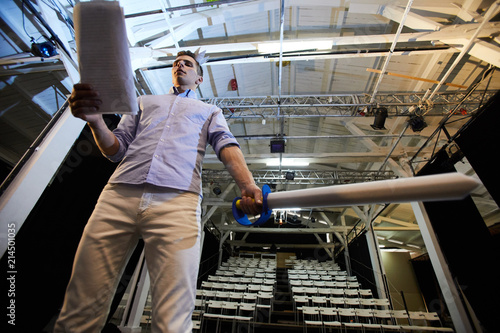 Young man with paper sword reading his speech during stage repetition process