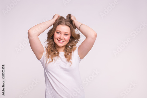 Happy white blonde girl with curly hair in white t-shirt, raising her hands in hair.