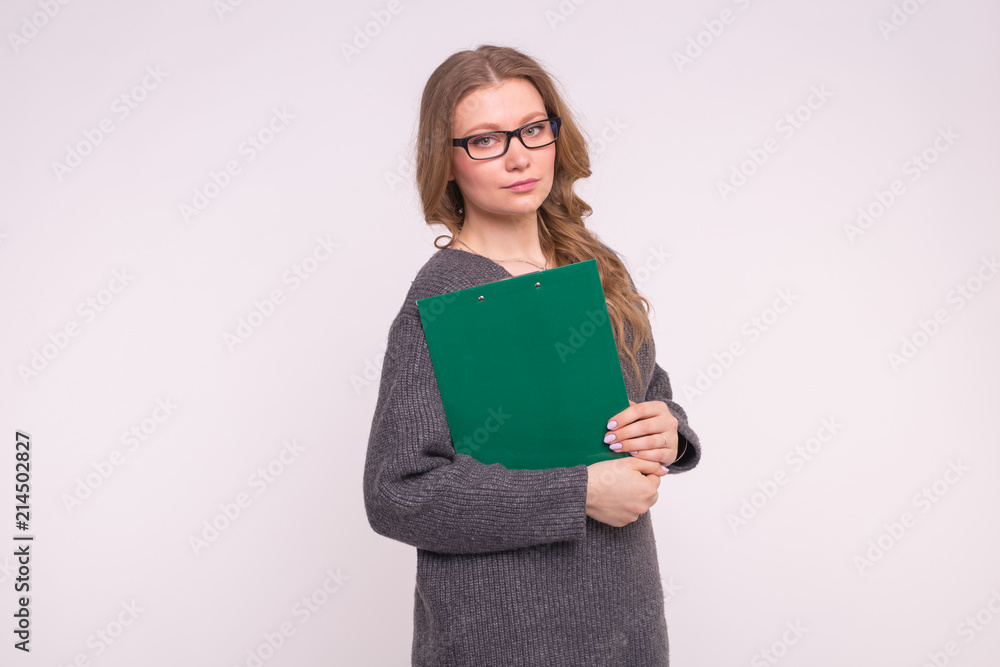 Smart beautiful girl in glasses with paper folder, wearing grey oversize sweater. Smart beautiful girl in glasses with paper folder, wearing grey oversize sweater.
