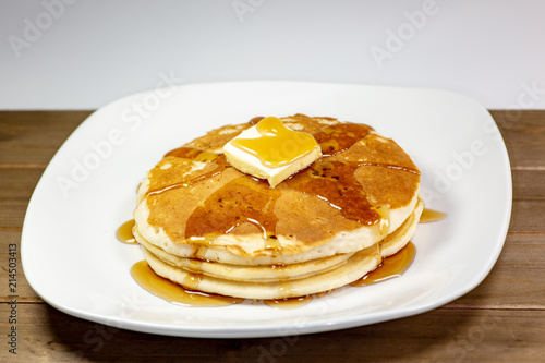Pancake with a square of butter and syrup on a kitchen table waiting to be eaten