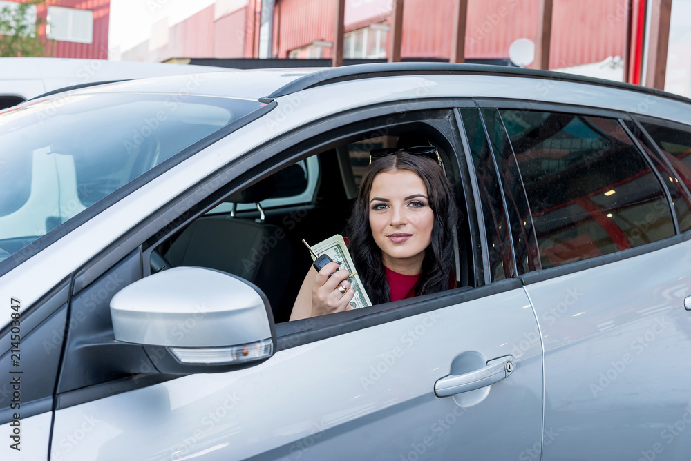 Woman showing dollar banknotes from car window Woman showing dollar banknotes from car window