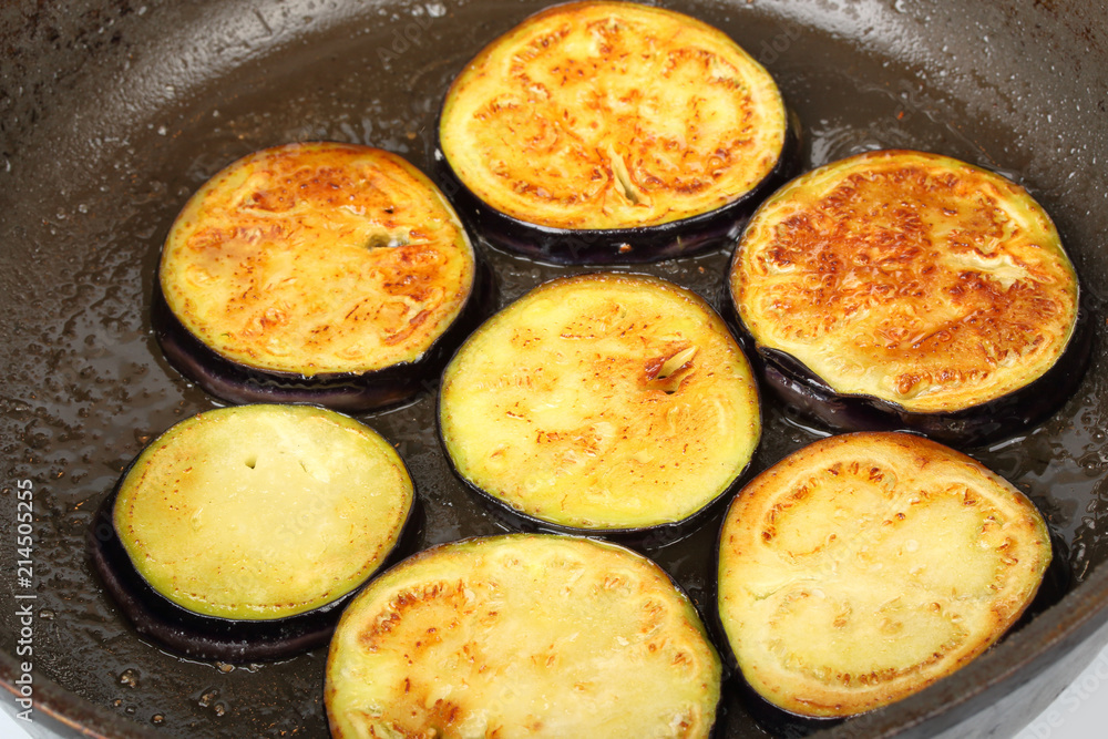 Sliced eggplants fry in a pot with oil Sliced eggplants fry in a pot with oil