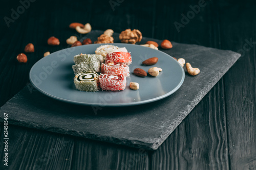 Traditional oriental sweets and nuts: hazelnuts, cashews on a dark wooden background. Turkish dessert is the Rakhat locus. View from above. Place under the text. photo