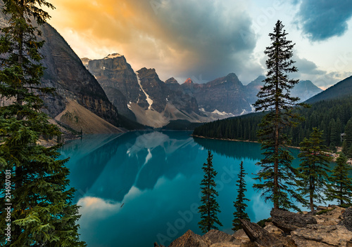 Sunrise with turquoise waters of the Moraine lake with sin lit rocky mountains in Banff National Park of Canada in Valley of the ten peaks. photo