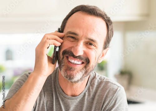 Middle age man using smartphone with a happy face standing and smiling with a confident smile showing teeth