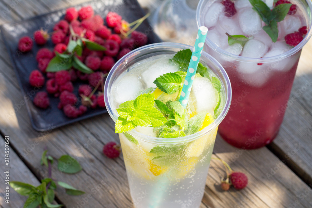 SOFT DRINKS. Refreshing summer drink lemon with mint, ice and raspberry with basil, ice. Glasses with cold and healthy beverage in a rustic style. SOFT DRINKS. Refreshing summer drink lemon with mint, ice and raspberry with basil, ice. Glasses with cold and healthy beverage in a rustic style.