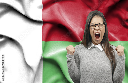 Ecstatic woman holidng fists and screaming against flag of Madagascar