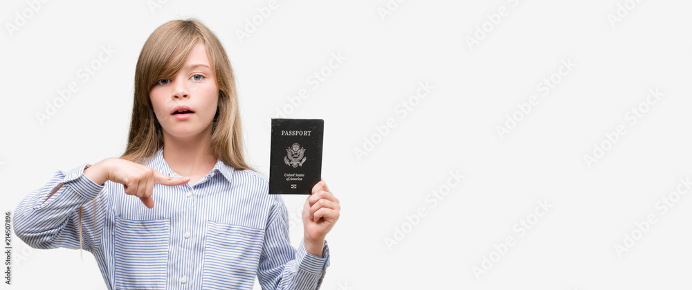 Young blonde toddler holding american passport very happy pointing with hand and finger Young blonde toddler holding american passport very happy pointing with hand and finger