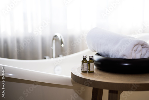 White towel and massage bath oil on table in bathroom.