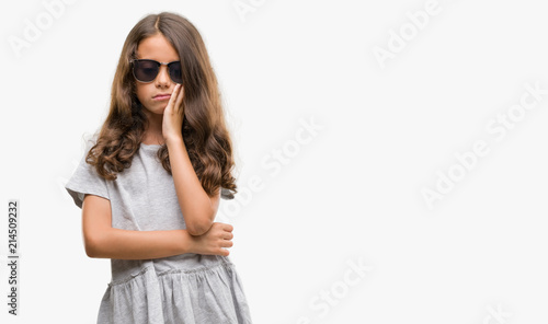 Brunette hispanic girl wearing sunglasses thinking looking tired and bored with depression problems with crossed arms. © Krakenimages.com