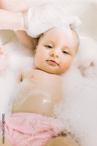 Happy little baby a swimming in the bathroom.Portrait of baby bathing in a bath with foam