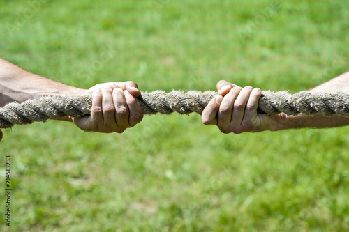 Two men's hands pull the rope each in his own direction. The concept of dispute, conflict and force