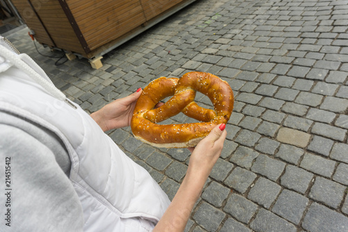 Girl on the street holding a pretzel in hand