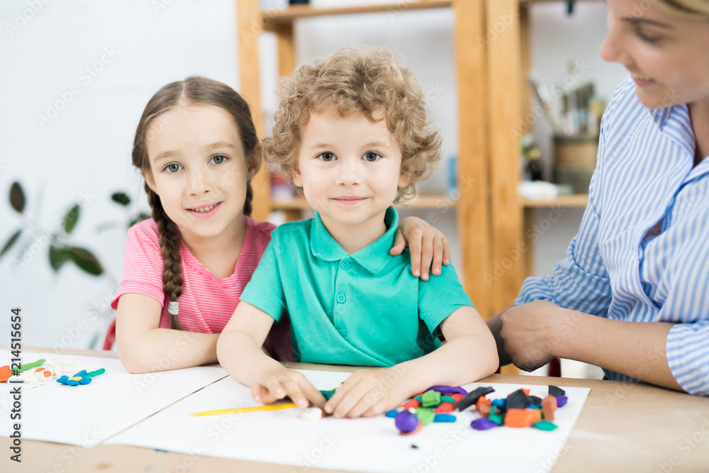 Portrait of little boy and girl embracing at the table while sitting in art and craft lesson Portrait of little boy and girl embracing at the table while sitting in art and craft lesson
