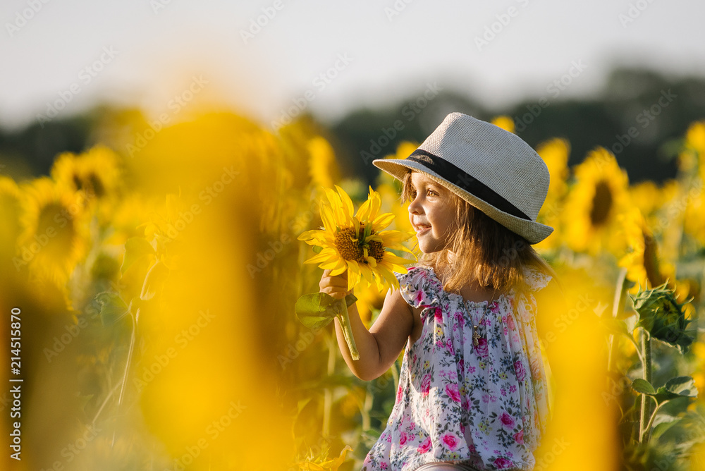 Fototapeta premium Happy little girl on the field of sunflowers in summer. beautiful little girl in sunflowers