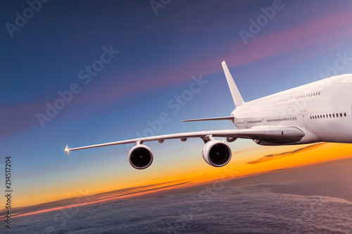 Big commercial airplane flying above dramatic clouds.