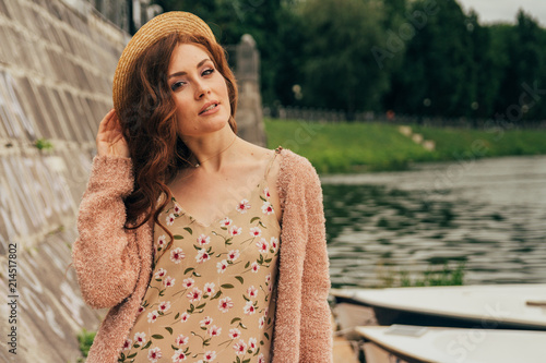 portrait a beautiful girl stands on the dock, near the wall and boats.