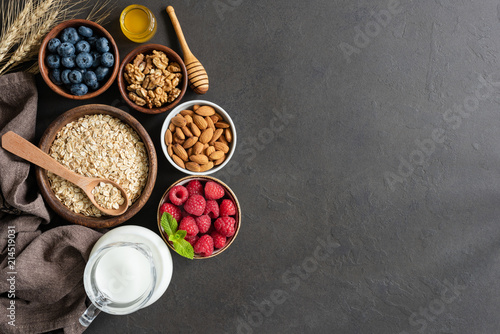 Nutrition Healthy Eating Ingredients on Black Concrete Background. Oats, Berries, Nuts, Almon Milk and Raw Honey. Healthy eating, Healthy lifestyle, Dieting