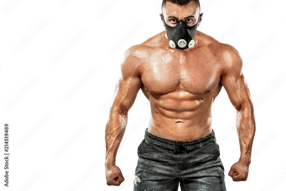 Brutal strong muscular bodybuilder athletic man pumping up muscles in training mask on white background. Workout bodybuilding concept. Copy space for sport nutrition ads. Brutal strong muscular bodybuilder athletic man pumping up muscles in training mask on white background. Workout bodybuilding concept. Copy space for sport nutrition ads.