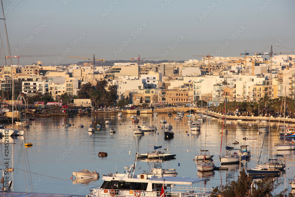 Yachts and boats reflected in blue water of harbour Sliema on dawn