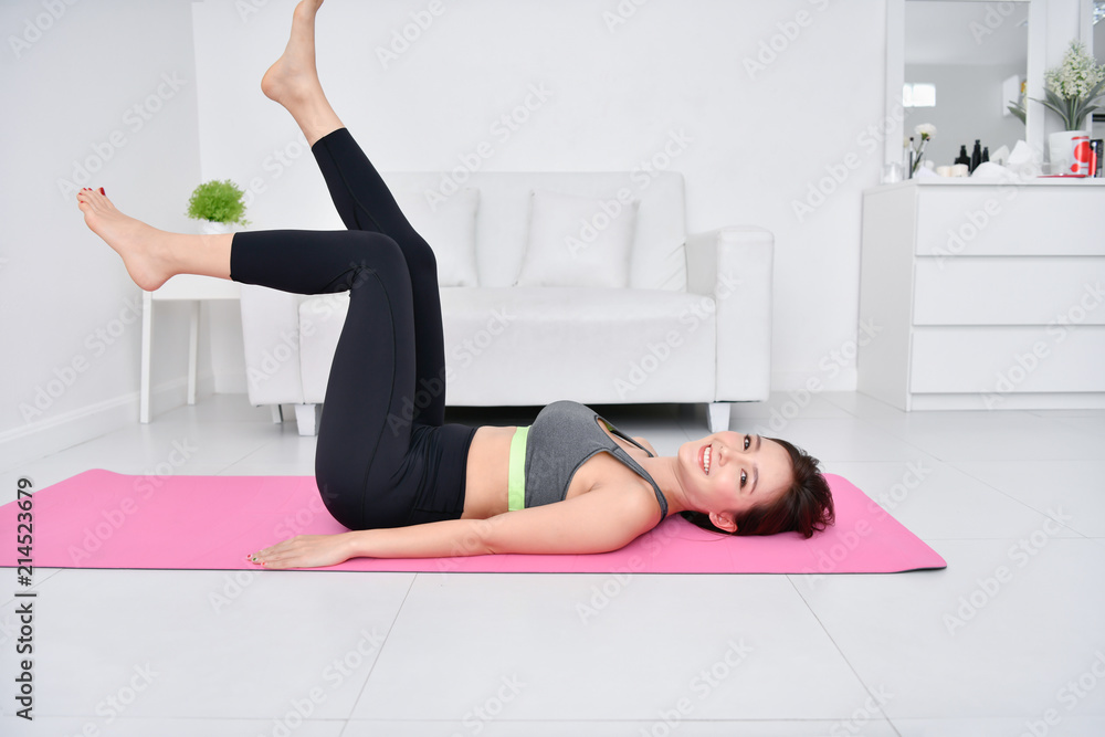 Fototapeta premium Concept of exercise. Beautiful girl is exercising in her house. Beautiful girl takes good care of her health.