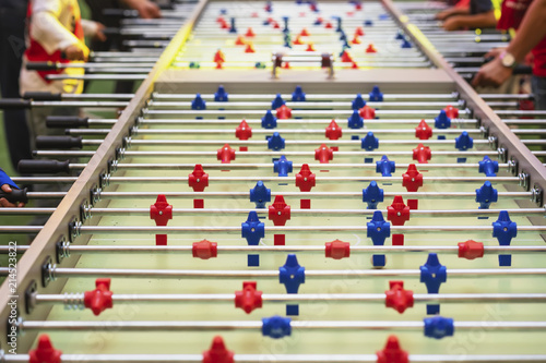 Table football game, soccer close-up and hands of people, selective focus. Soccer table with red and blue plastic players, foosball
