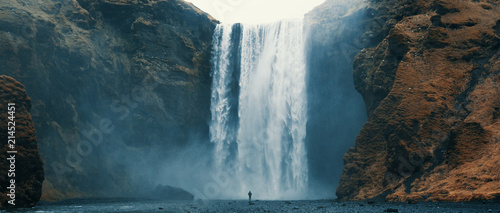 Fotografie, Obraz Woman overlooking waterfall at skogafoss, Iceland