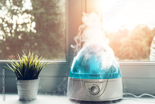 Air humidifier during work. The white humidifier moistens dry air. Improving the comfort of living in the home, apartment. Improving the well-being of people. photo