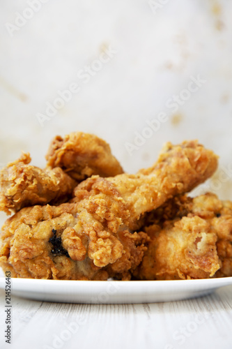 Fried chicken legs on a white round plate, closeup. Side view.