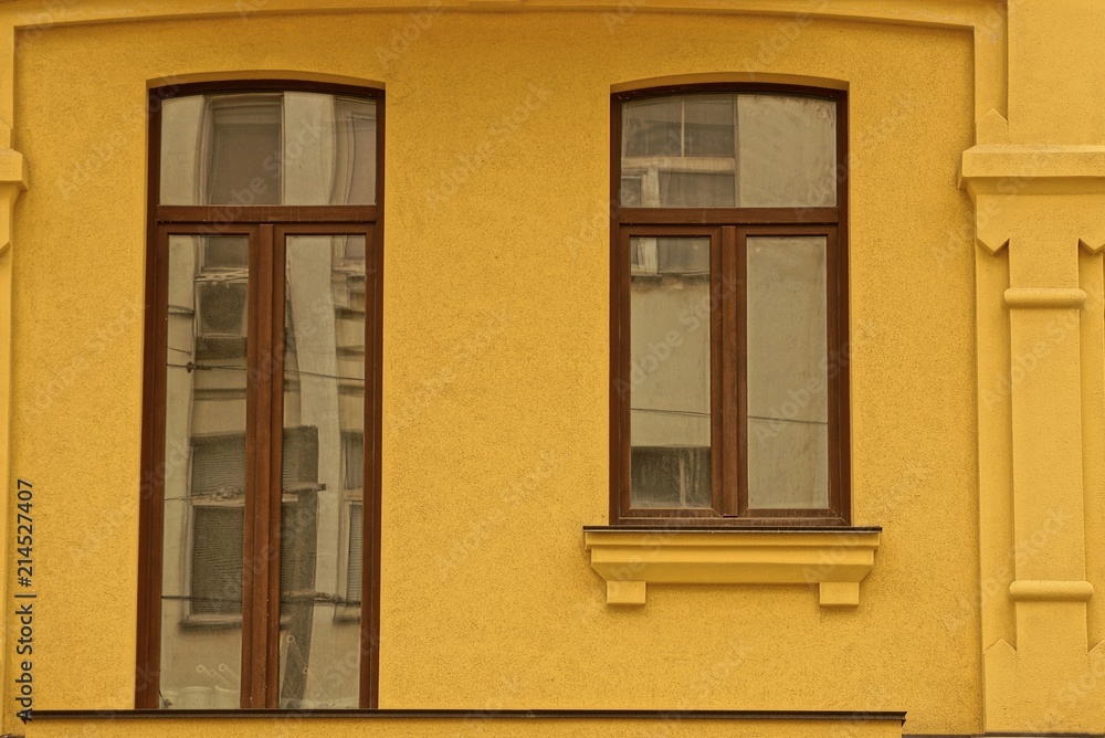 two modern windows on the brown wall of the house