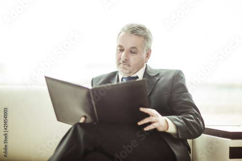 successful businessman studies working papers sitting on the sofa in the private office