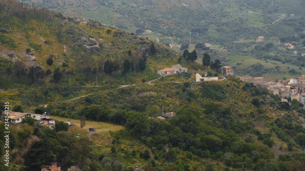 Pan from small houses in the middle of trees to a small town between hills Pan from small houses in the middle of trees to a small town between hills