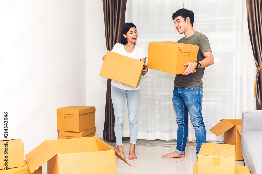Happy young couple holding box and moving into their new home.House moving and real estate concept Happy young couple holding box and moving into their new home.House moving and real estate concept