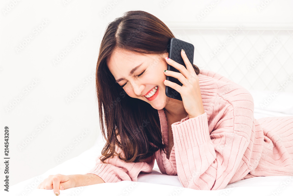 Happy woman relaxing using and talking by smartphone on the bed at home.technology and communication concept Happy woman relaxing using and talking by smartphone on the bed at home.technology and communication concept