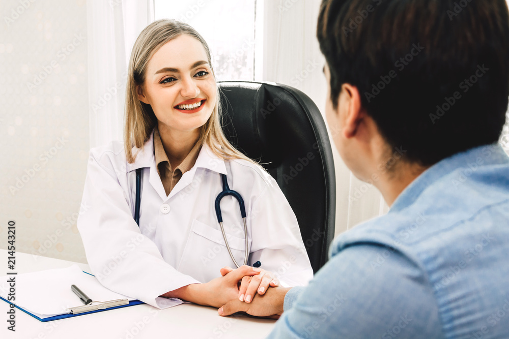 Female doctor consulting and holding hand male patient reassuring with care on doctors table in hospital.healthcare and medicine Female doctor consulting and holding hand male patient reassuring with care on doctors table in hospital.healthcare and medicine