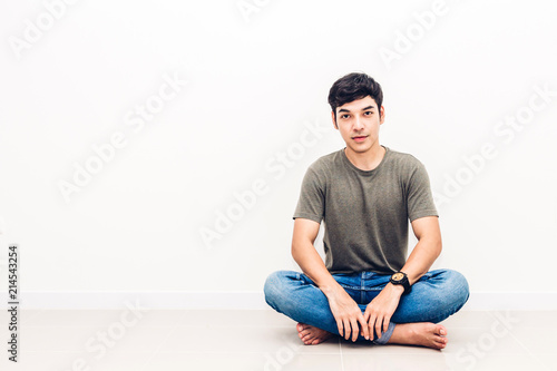 Handsome man sitting relax on floor against copy space for adding text with white wall background