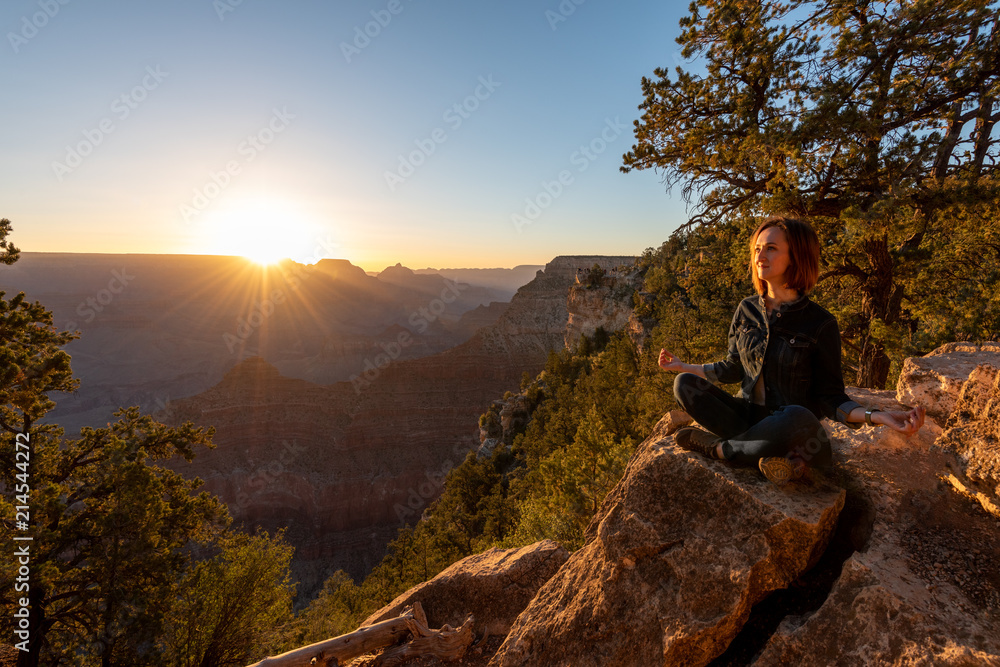 Girl is Seating and Doing Yoga on the Edge of Grand Canyon on Sunrise