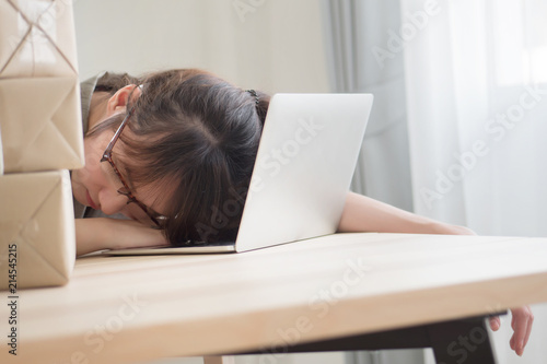 exhausted asian woman business working overnight and sleep at work desk; portrait of tired, exhausted, overworked business woman sleeping with tireness on work station; adult asian chinese woman model