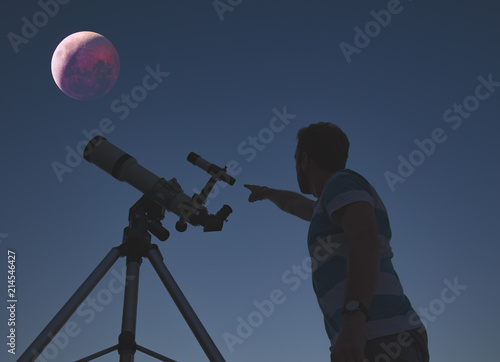 Man looking at lunar eclipse through a telescope. My astronomy work.