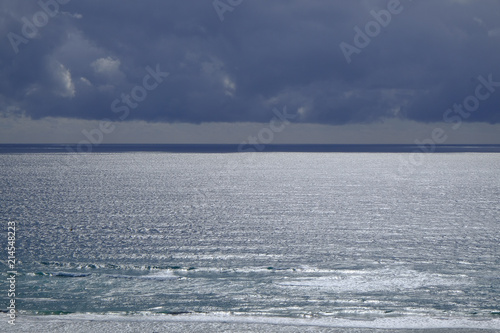 Silver light on the ocean under approaching storm clouds