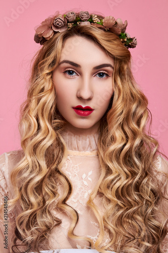 Fashion photo of young woman on pink background wearing gold diadem