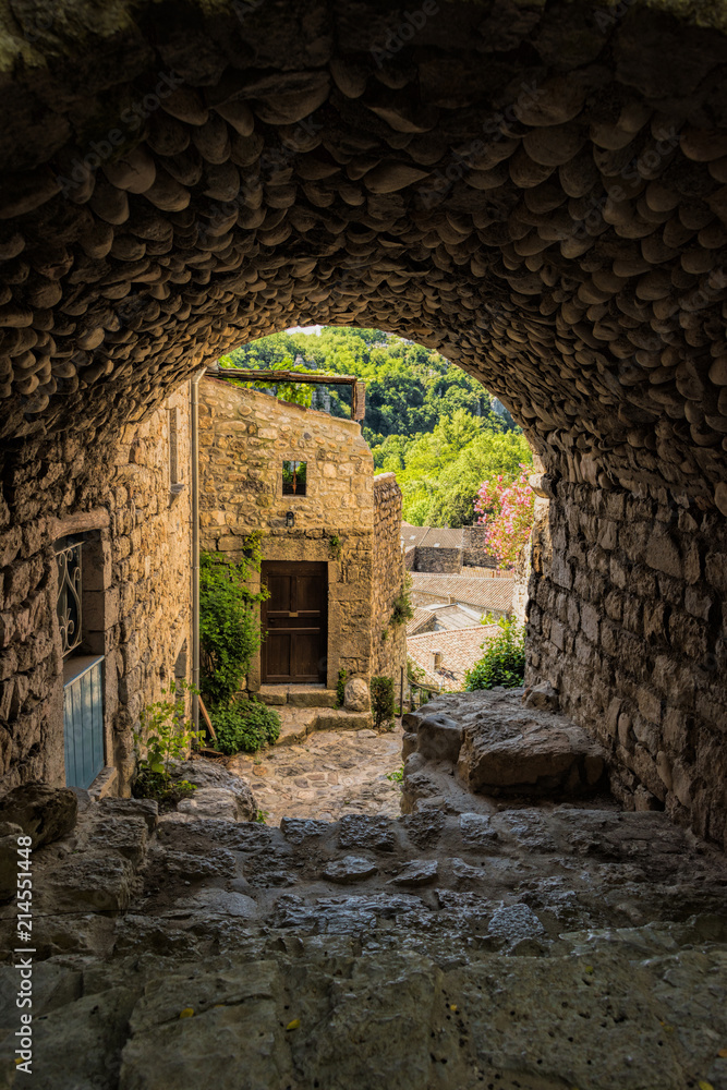 View into a backyard with a stone archway and cobblestone passageway in the medieval village Labeaume at the Ardeche river in France