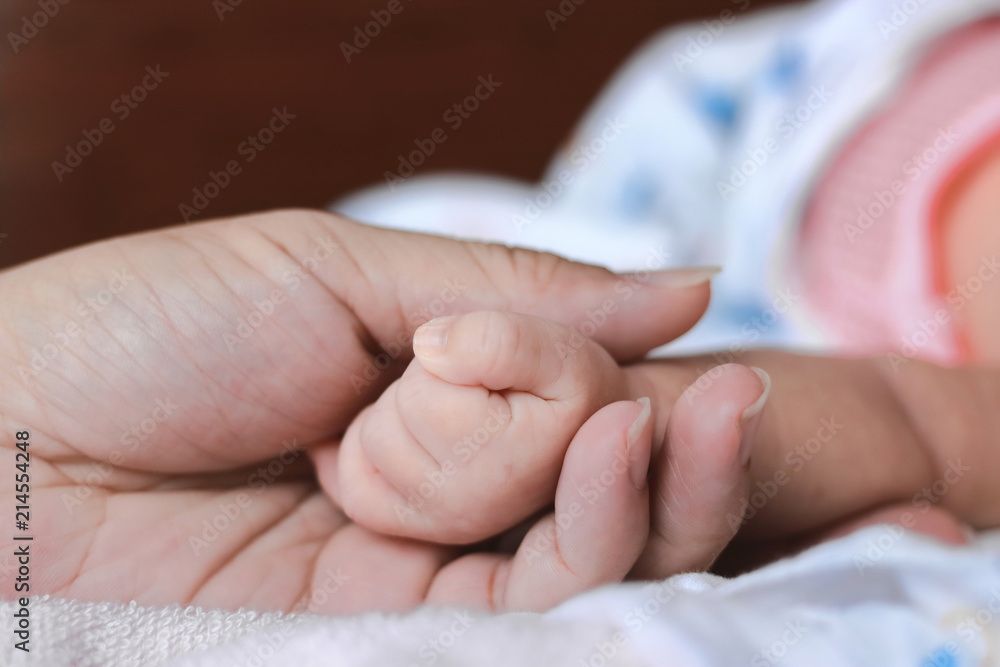 Selective focus on hands of newborn tiny baby and parents.