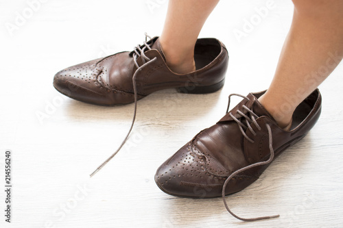 small child, dressed in brown shoes large adult. the child wore dad's shoes