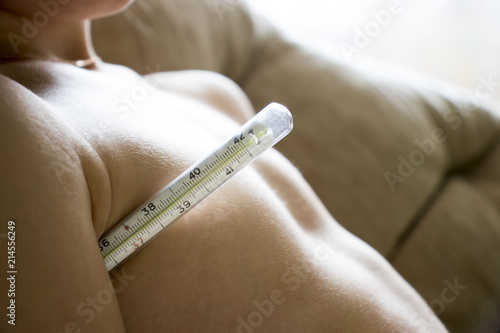 child measures the temperature with a thermometer under the mouse sitting in a chair, the concept of disease, treatment photo