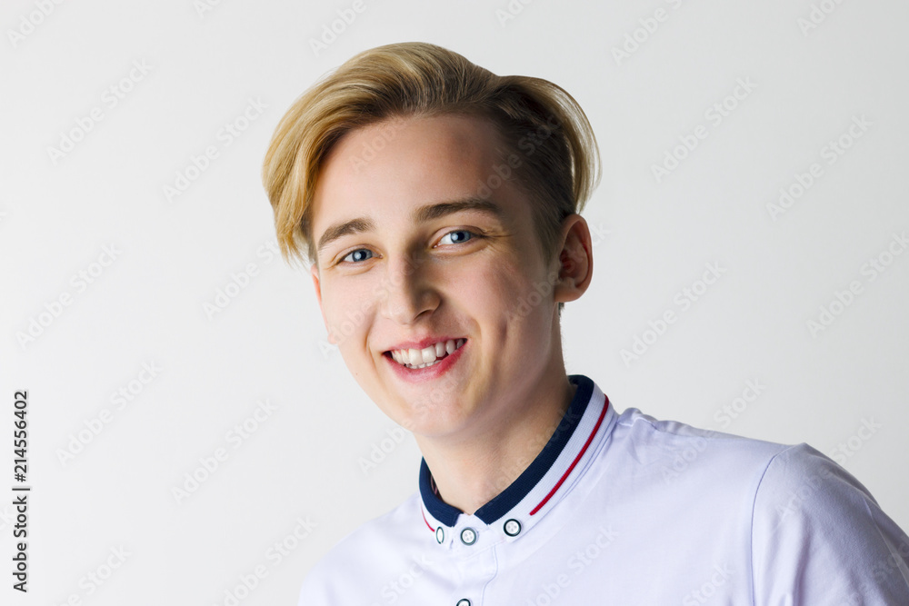 Handsome boy teenager in white shirt smiles in white studio, close up Handsome boy teenager in white shirt smiles in white studio, close up
