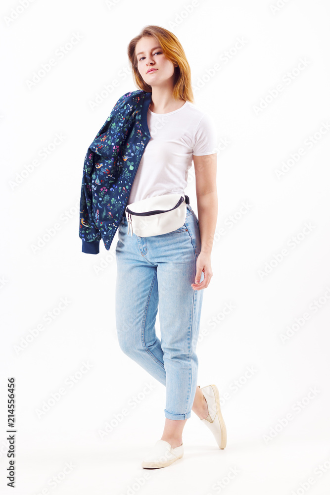 Beautiful girl teenager in bomber and jeans poses in white studio, full body Beautiful girl teenager in bomber and jeans poses in white studio, full body