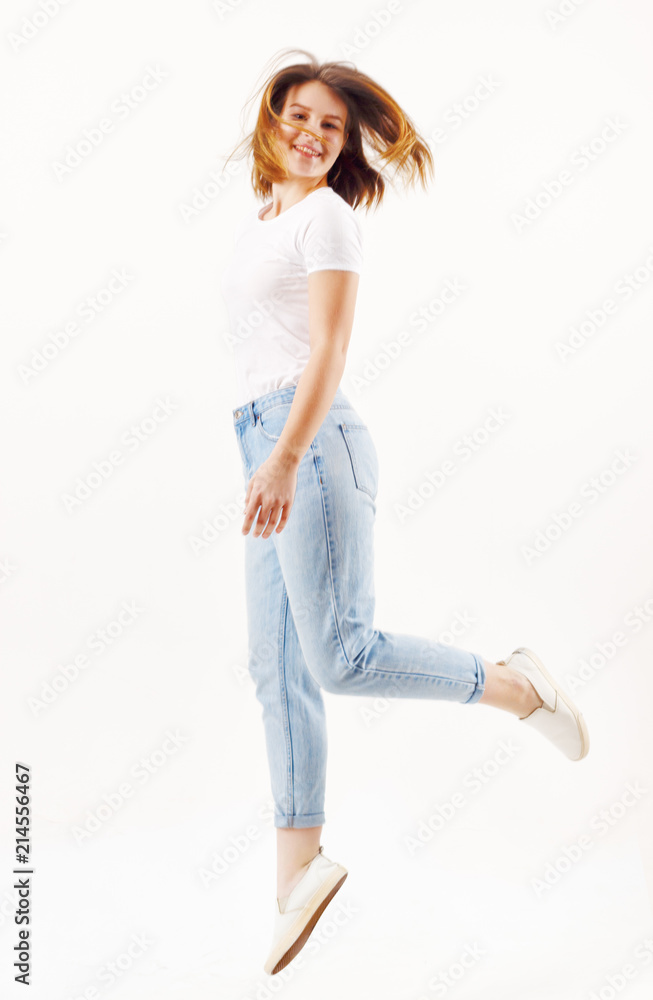 Happy girl teenager in t-shirt and jeans jumps in white studio, full body Happy girl teenager in t-shirt and jeans jumps in white studio, full body